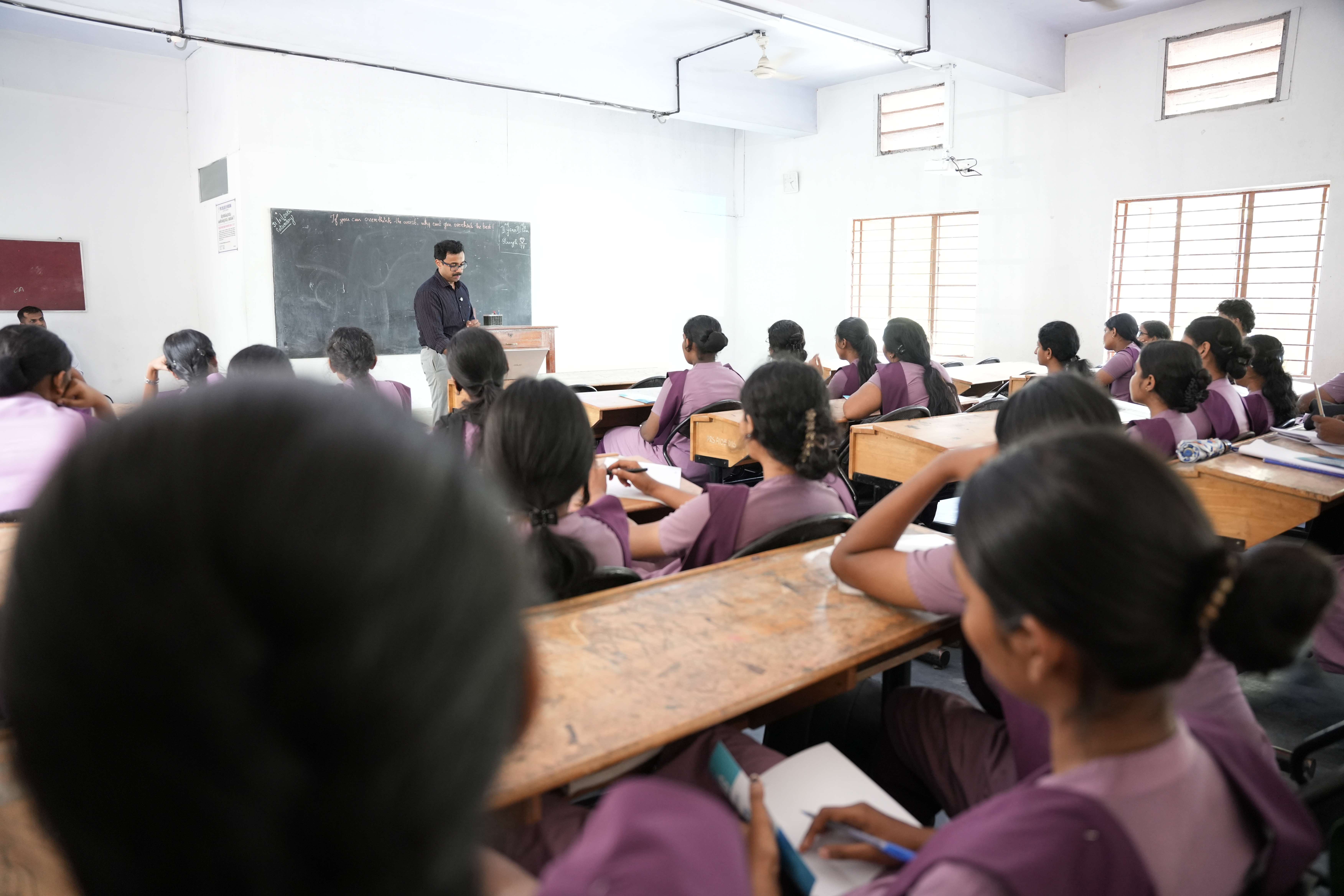 Faculty member interacting with a student at the teacher's desk