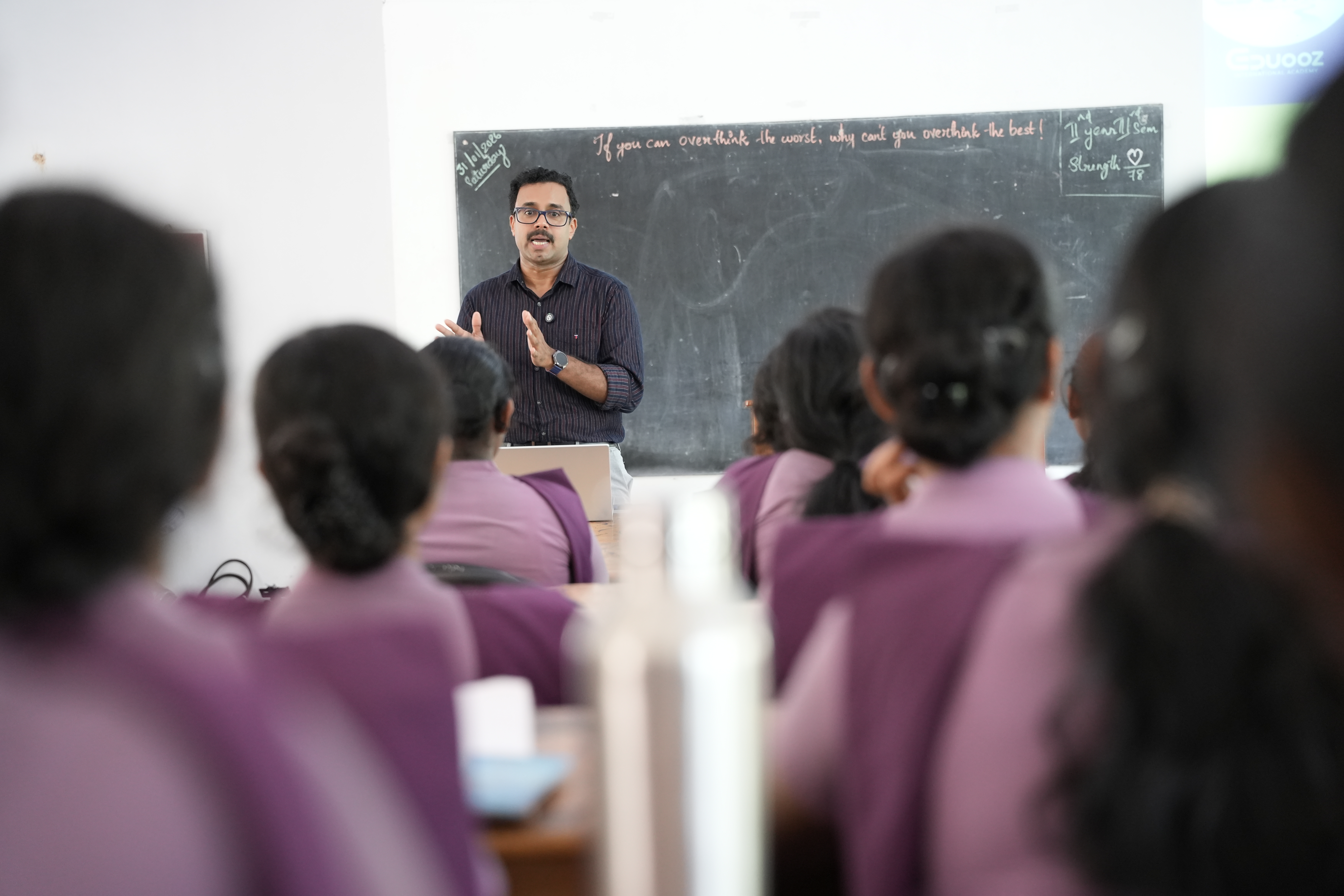 Mentor holding a microphone while addressing students in green uniforms