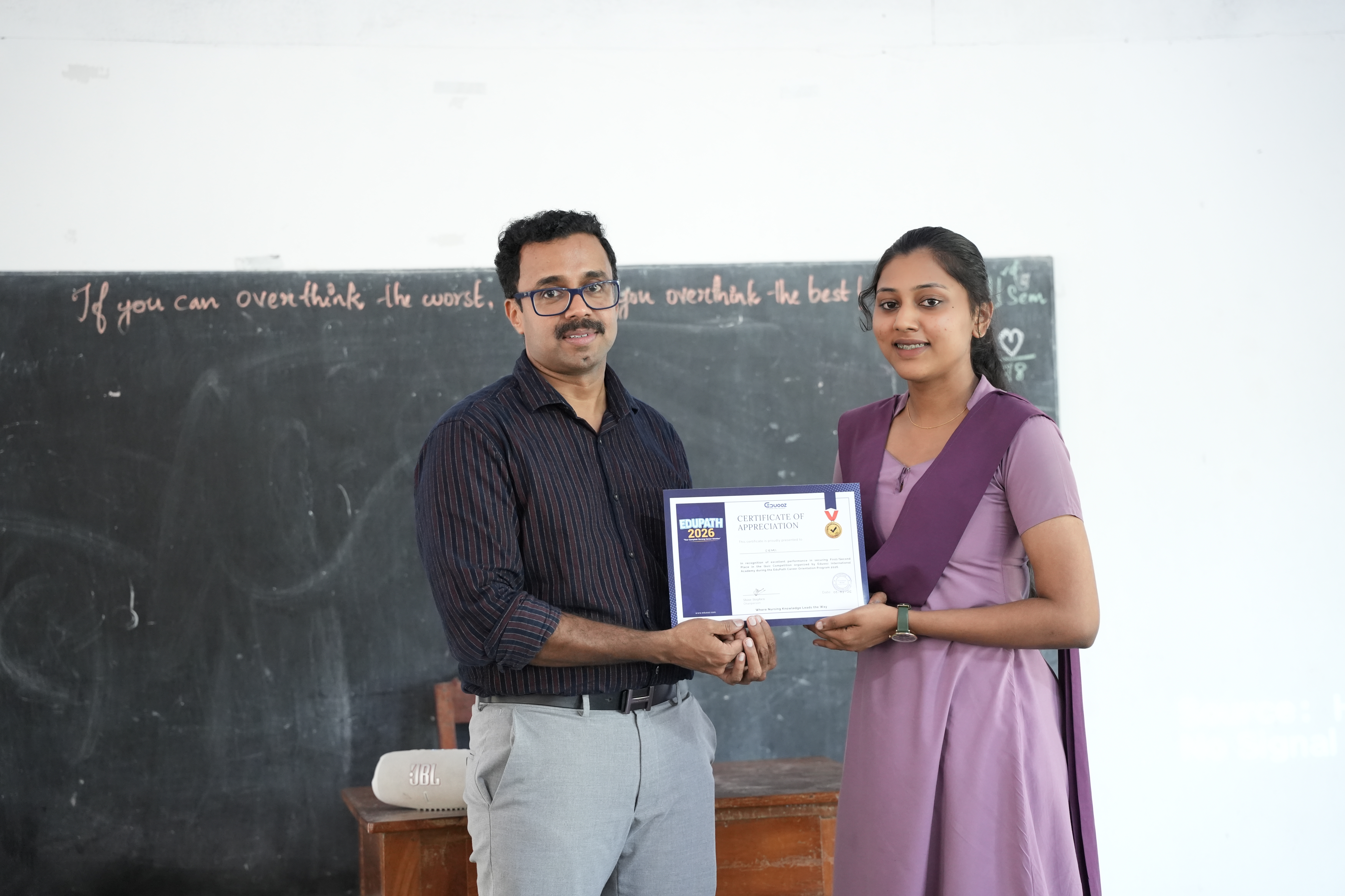 Two mentors presenting a certificate to a student together